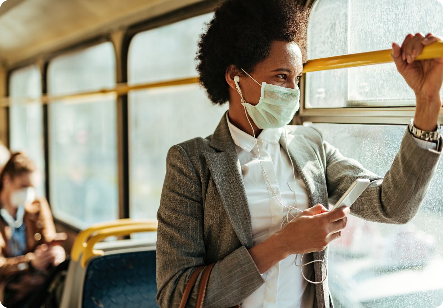 African American woman standing on a bus wearing a face mask for protection against COVID-19