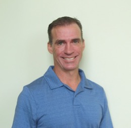 Male healthcare provider smiling and wearing a blue polo shirt