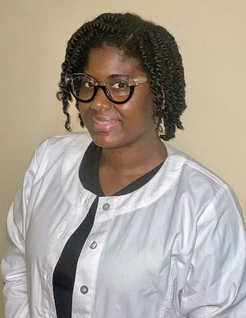 Female registered nurse wearing glasses and a white jacket, smiling