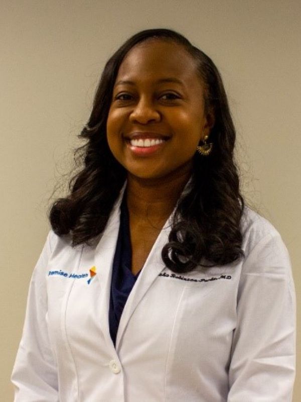 Smiling female healthcare provider wearing a white Premise Health lab coat
